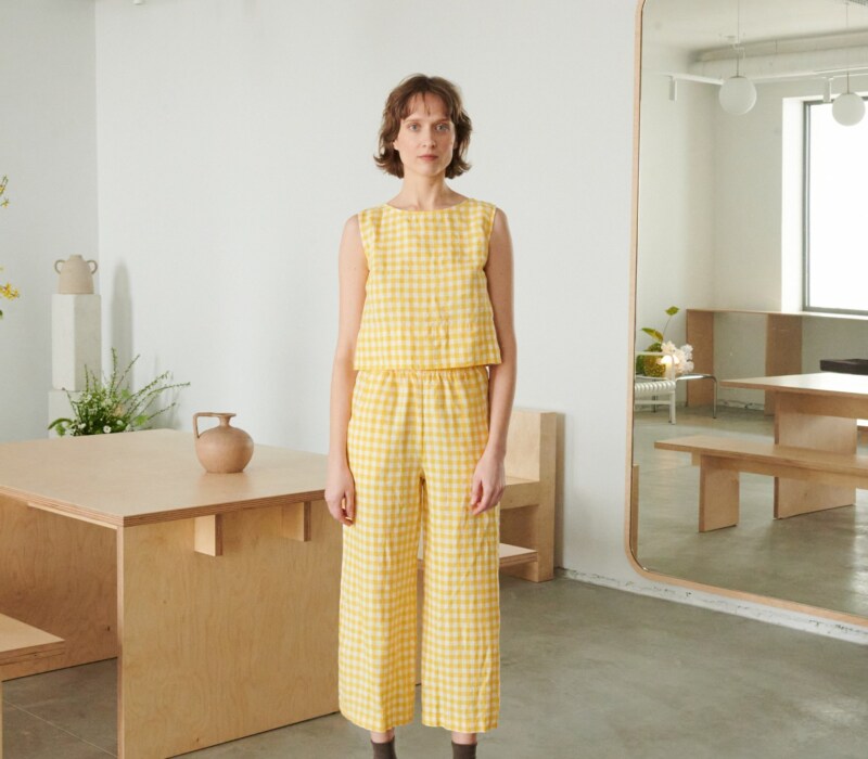 A woman in relaxed yellow gingham linen pants