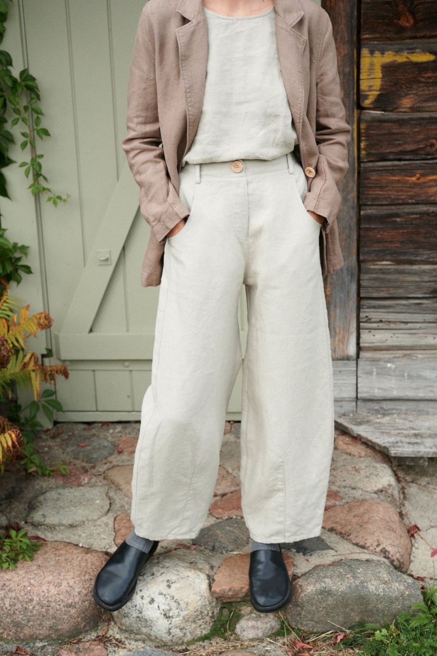 A woman in high waist barrel leg natural linen pants