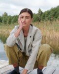 A woman squatting in olive green heavy linen trousers