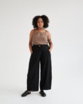 A woman wearing black linen barrel trousers.