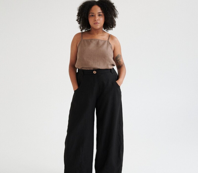 A woman wearing black linen barrel trousers.