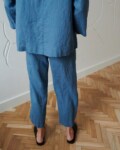 Back of a model in loose-fitting linen trousers and an oversized linen tunic