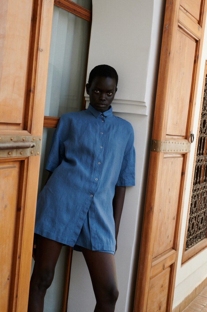model wearing a linen set of short-sleeved linen shirt, and wide shorts in stellar blue