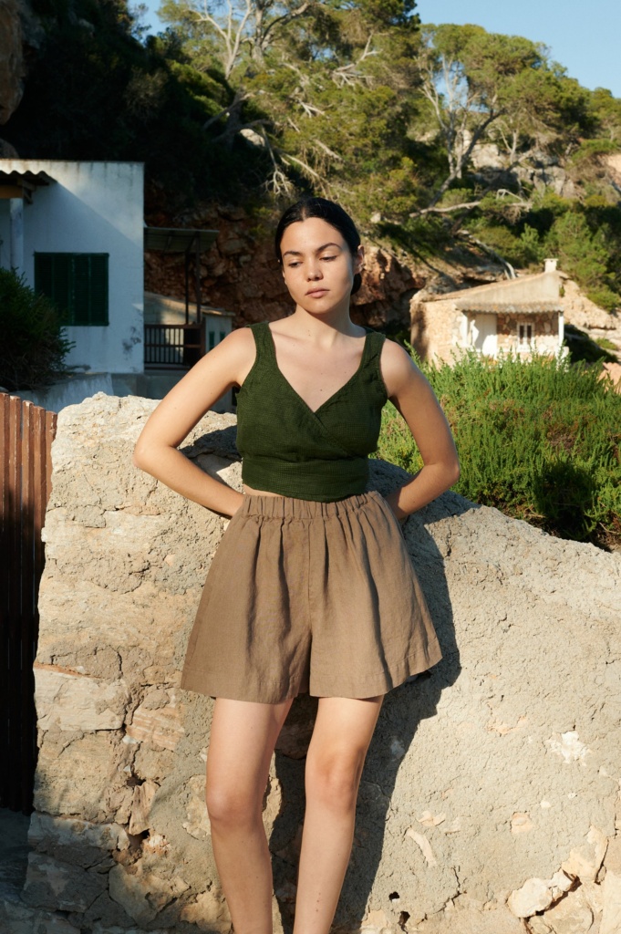 Model wearing Kim linen shorts that resemble a skirt, styled with a wrap blouse