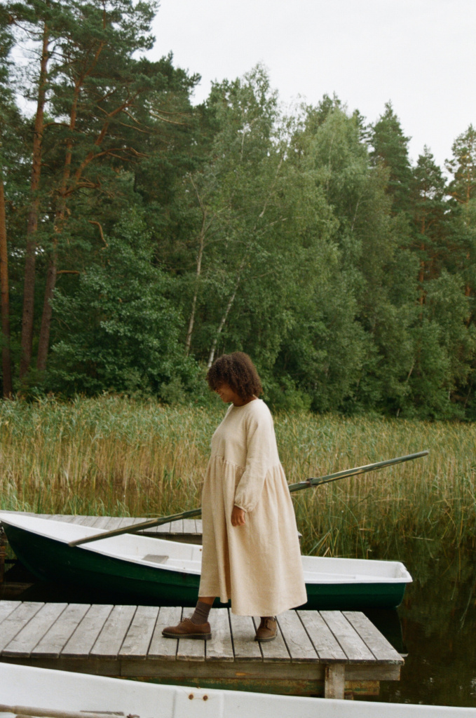 a woman near the lake wearing a long dress in beige linen wool blend