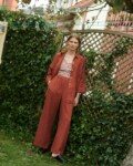 model in a garden wearing a terrracotta gingham linen wrap top and wide leg linen trousers and shirt in terracotta linen
