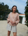 Model wearing lightweight cacao stripes linen shorts and an oversized long sleeve peach linen wrap top outfit