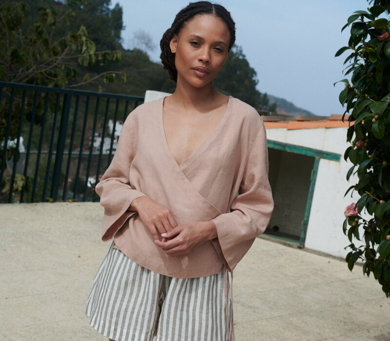 Model wearing lightweight cacao stripes linen shorts and an oversized long sleeve peach linen wrap top outfit