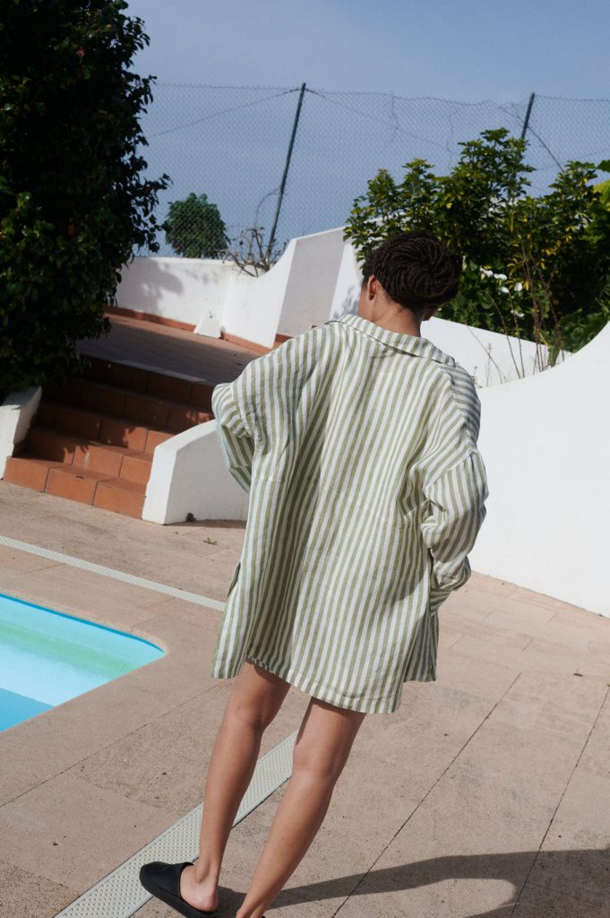 Back view of a model in an oversized lightweight olive stripes linen shirt
