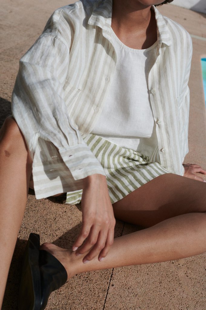 Model wearing a casual oversized linen shirt with shell buttons and linen shorts outfit