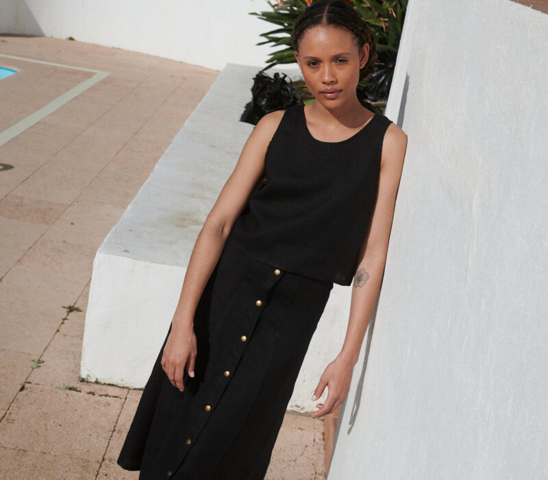 Model wearing a black midi skirt paired with a matching casual sleeveless black linen top