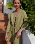 a woman wearing a linen set featuring a tie-up front top paired with a short skirt in olive linen fabric