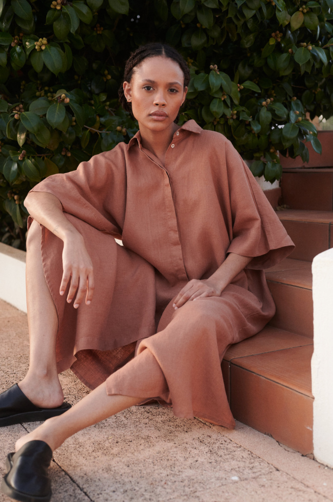Model sitting in an oversized linen dress with hidden buttons and short kimono sleeves
