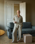 Model wearing high-waisted, wide-leg pants in lightweight natural grey linen and a matching relaxed button-up shirt with shell buttons
