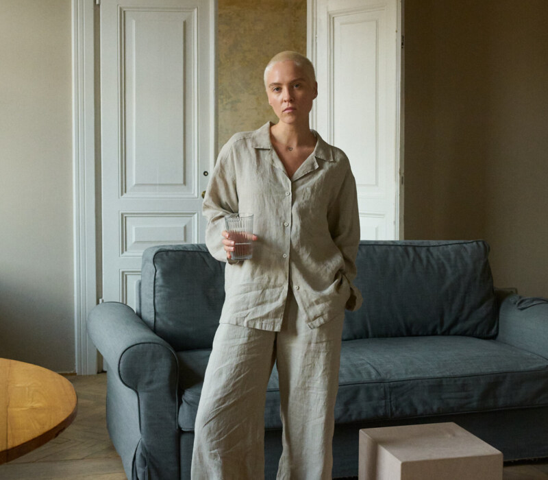 Model wearing high-waisted, wide-leg pants in lightweight natural grey linen and a matching relaxed button-up shirt with shell buttons