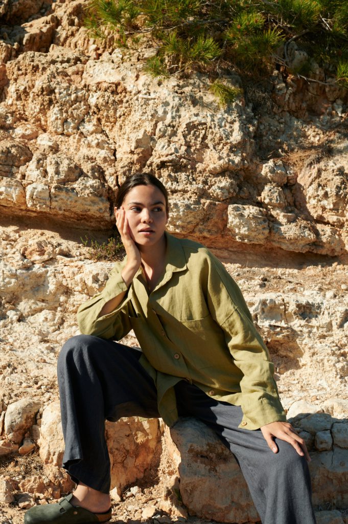 Model wearing a relaxed-fit linen button-down shirt tucked into high-waisted trousers