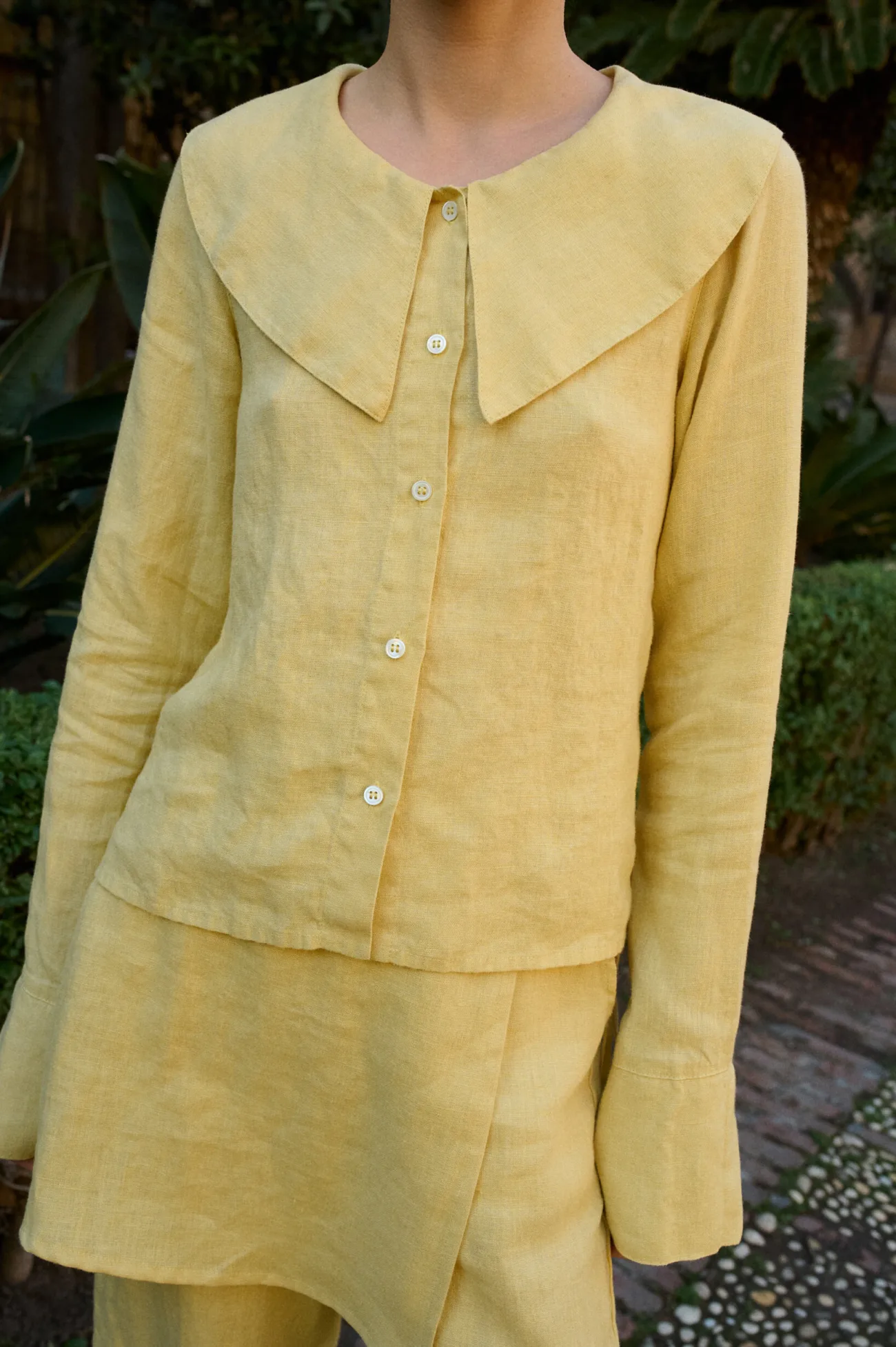Model wearing a butter-yellow linen blouse with a bold oversized collar, offering a stylish and relaxed fit