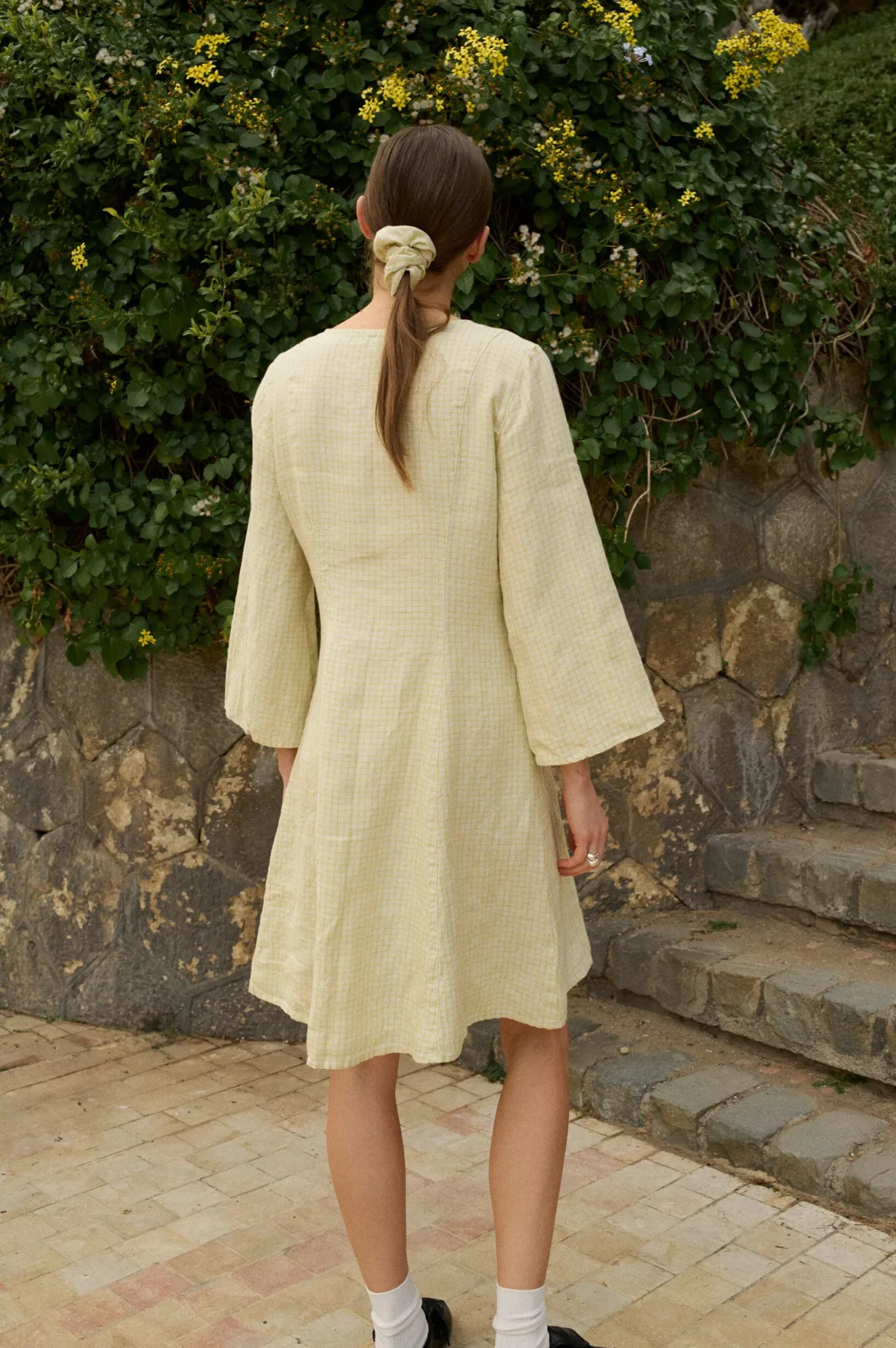 Model in a pale apple-green check pattern dress with wide three-quarter length sleeves and a tailored bodice that flares to an A-line shape