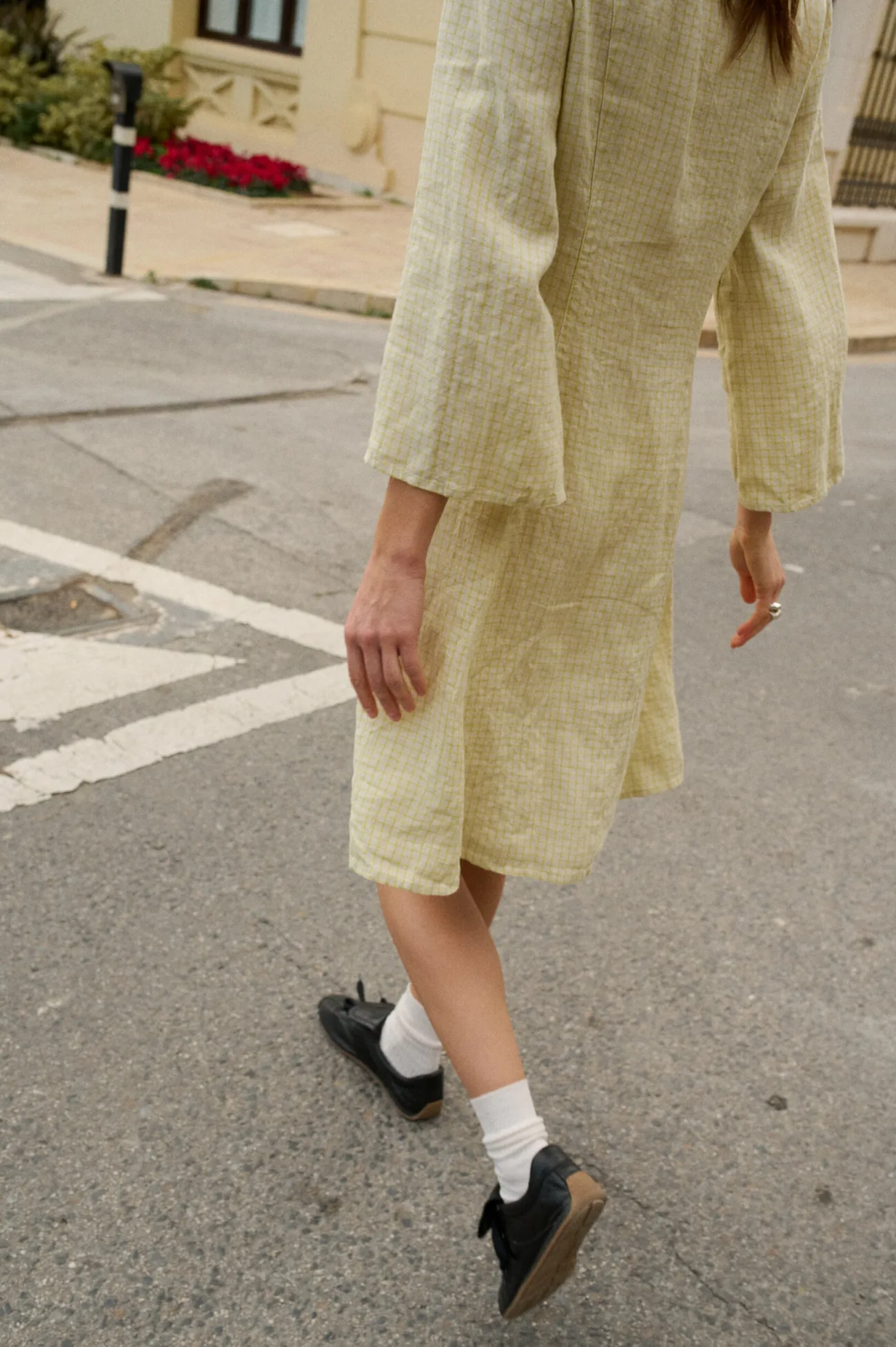 Model walking away, wearing a apple-green check pattern knee-length linen dress with wide three-quarter length sleeves