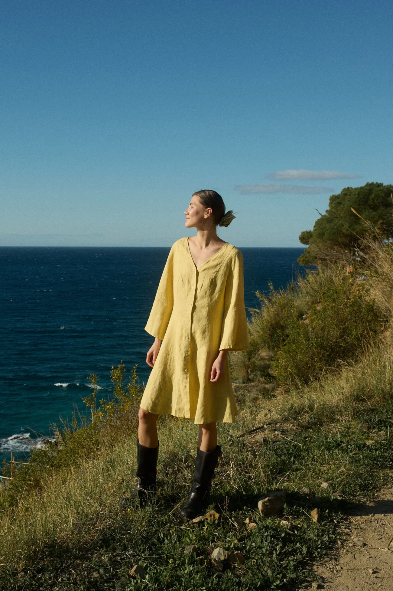 Model in a yellow linen dress featuring a V-neck, button-down design, ¾ flared sleeves, and a flowing A-line fit, enhanced with vertical panels and godet inserts for a graceful, airy look