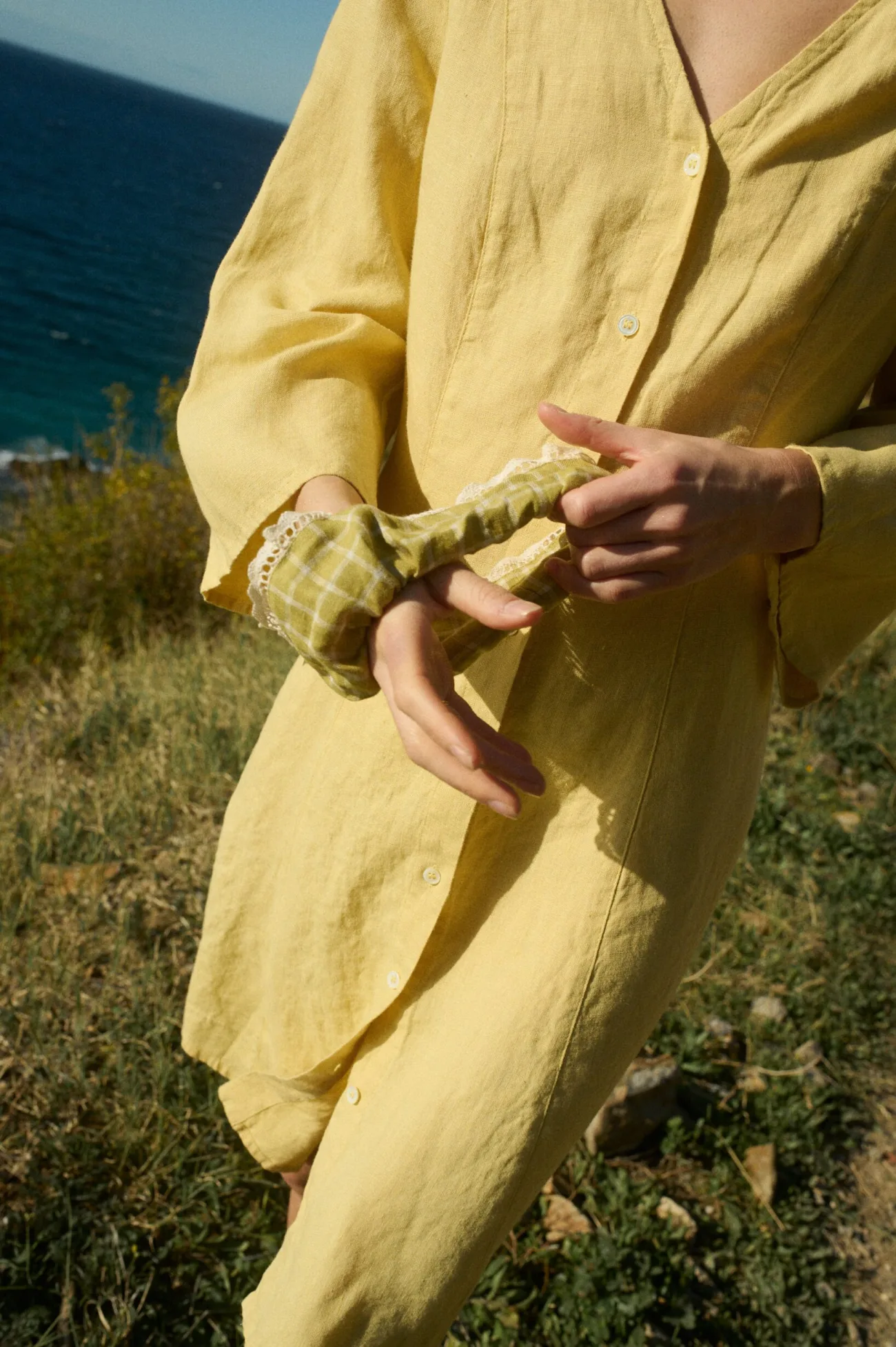 A pickle checks linen scrunchie with white lace trim, held on the wrist and pulled gently with the other hand