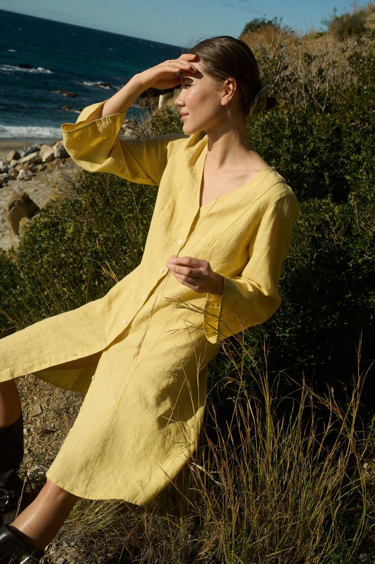 Model showcasing a yellow linen dress with a V-neck, button-down front, ¾ flared sleeves, and a relaxed A-line silhouette, adorned with vertical linen panels and godet inserts for added movement and elegance