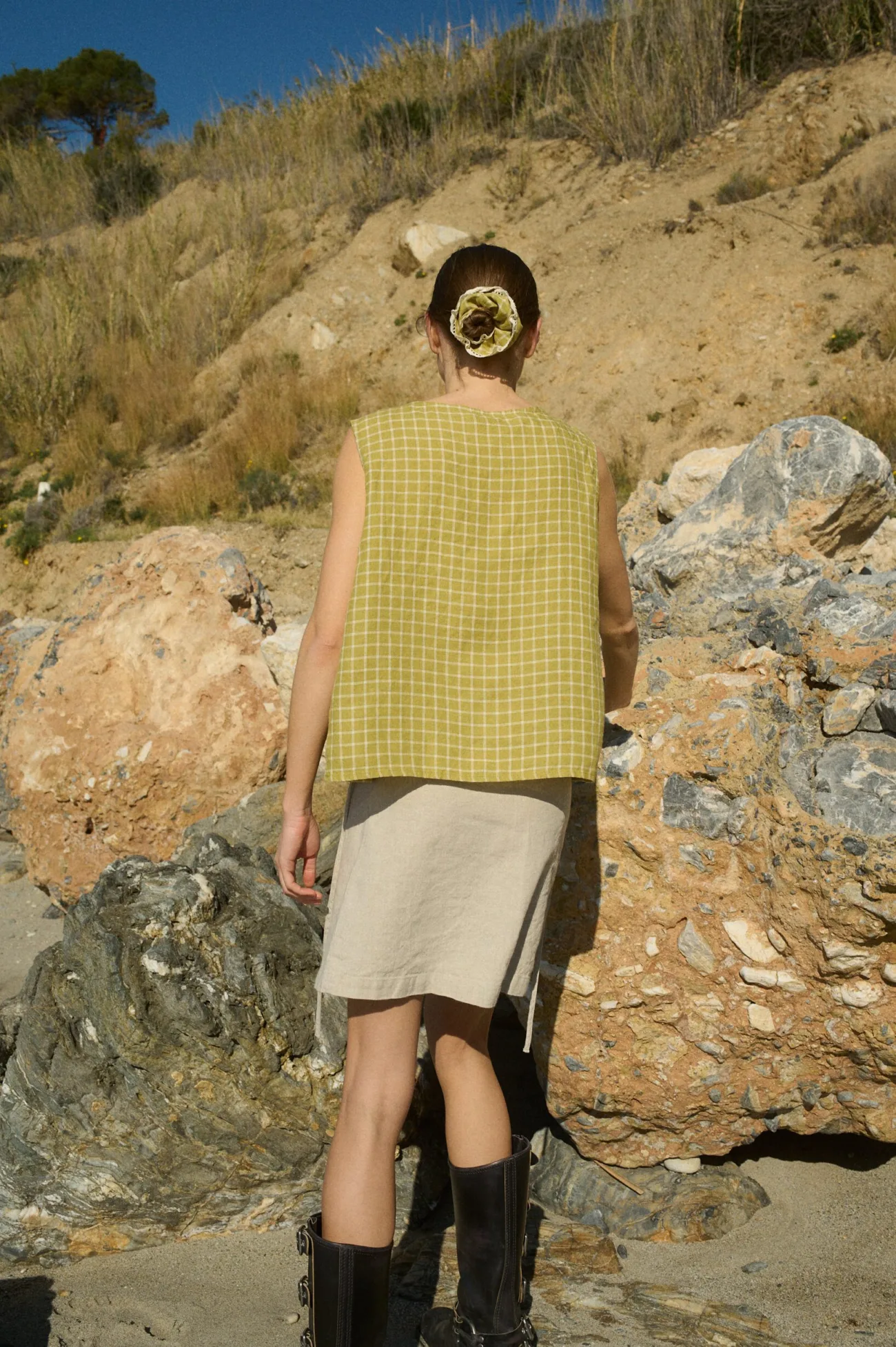 Model wearing a relaxed-fit sleeveless wrap top in pickle checks grid-patterned linen, paired with a natural-toned mini skirt made from a soft cotton blend
