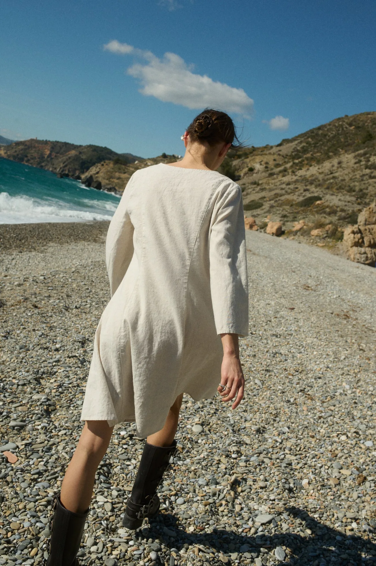 Model shown from the back, wearing a white cotton blend dress with three-quarter sleeves that slightly flare at the ends and a flared A-line shape that falls to a knee-length hem
