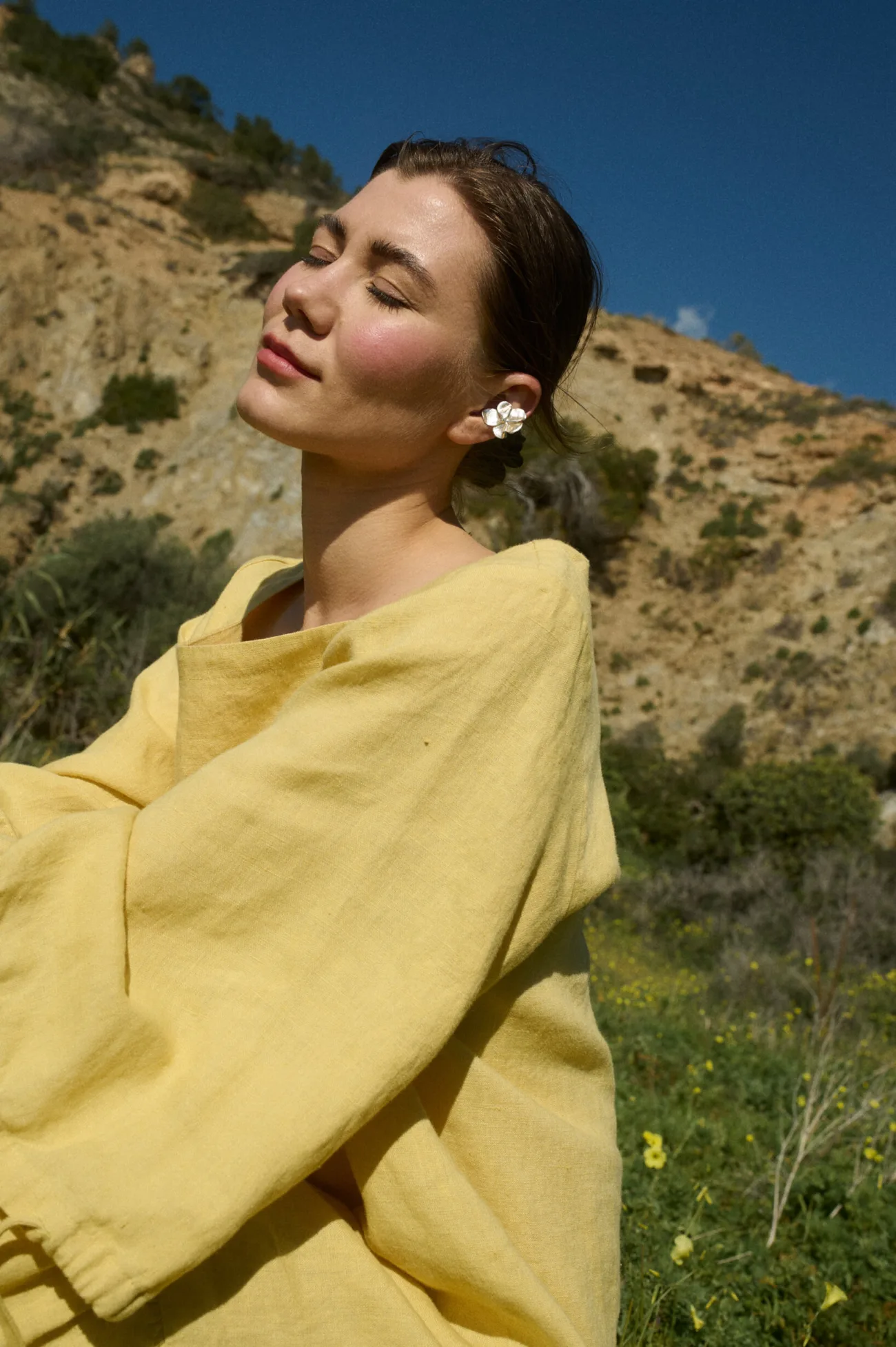Model wearing a loose-fitting pale yellow colored linen dress featuring sleeves with tie details