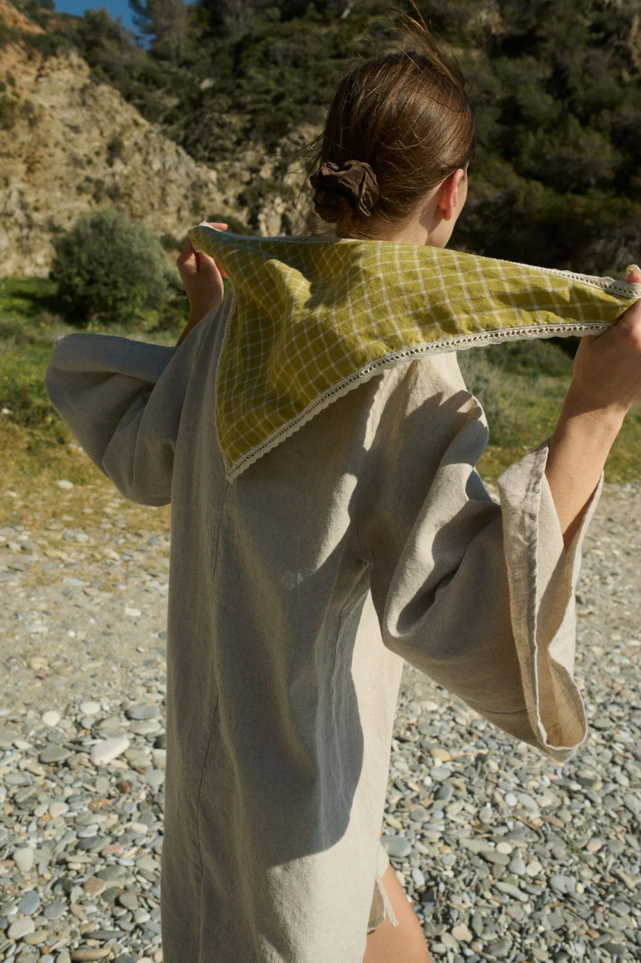 Woman holding a linen bandana in a pickle checks pattern with subtle white lace trim behind her back