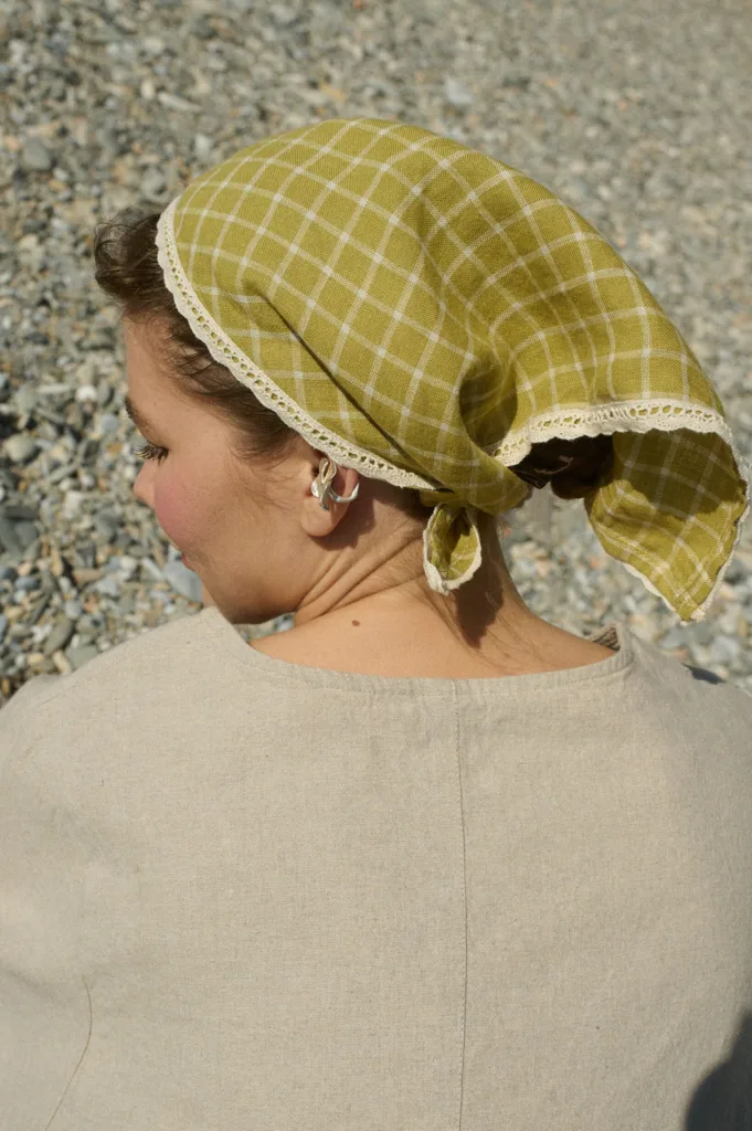 Model wearing a linen bandana in a pickle checks pattern with delicate white lace trim, tied around her head