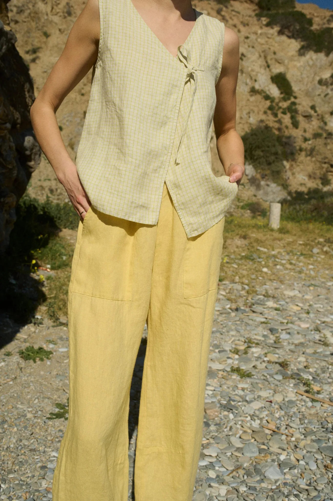 A relaxed-fit sleeveless V-neck top in airy apple checks linen with a delicate side tie, paired with butter yellow wide-leg linen pants accented with patch pockets