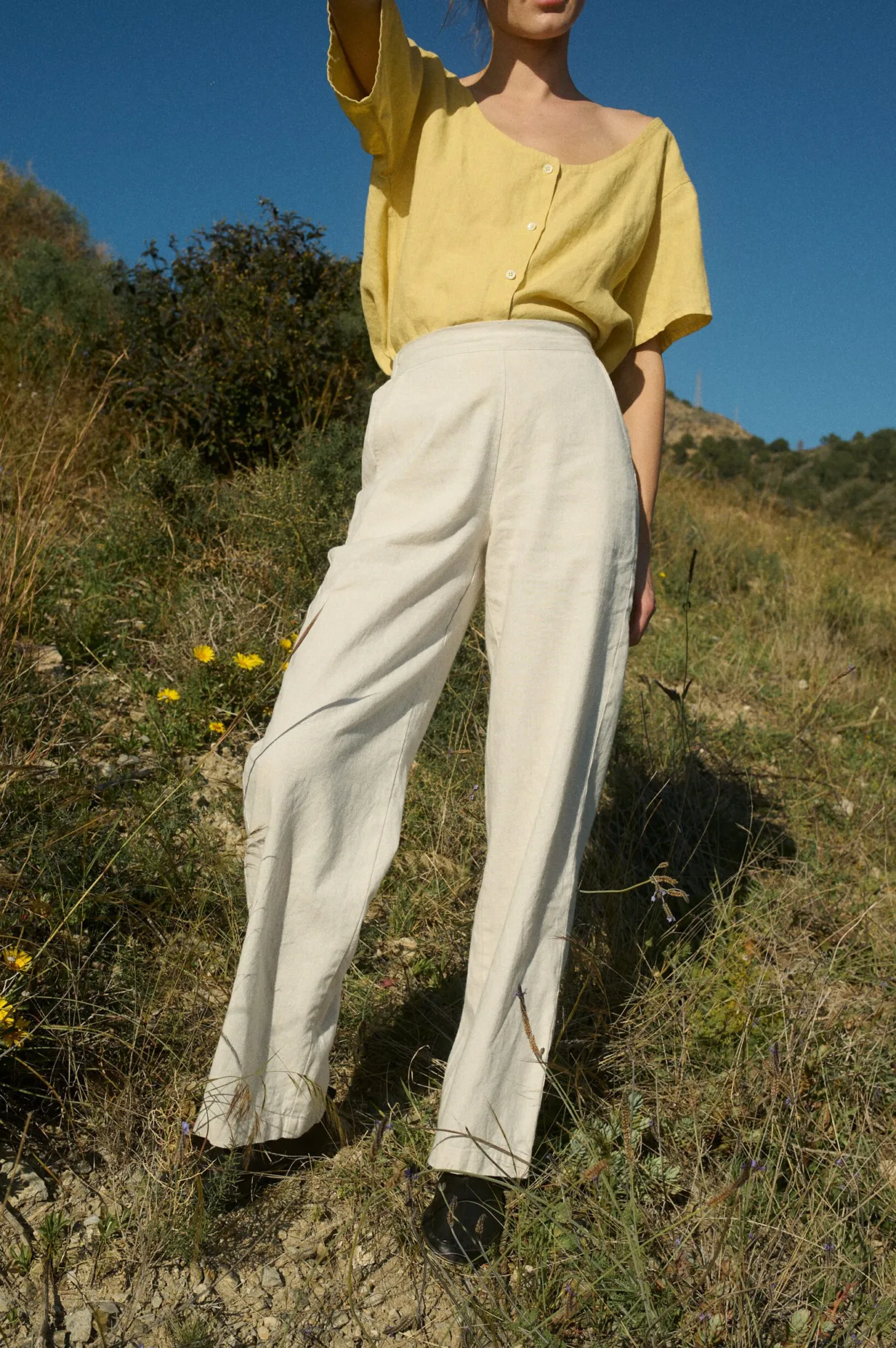 The front view showcases the vibrant sunshine-yellow linen top with a scoop neckline and button details, paired with breezy cream wide-leg pants for a light, effortless look