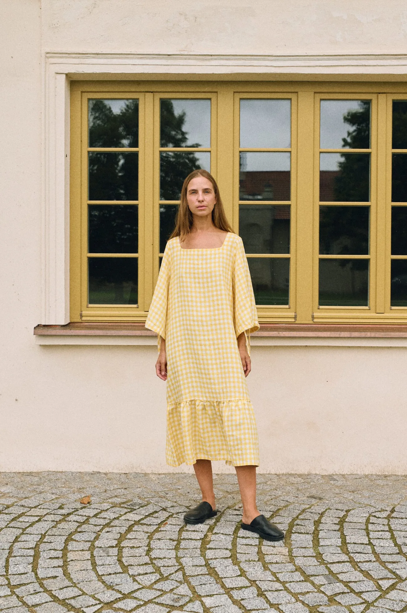 Full length front view of yellow gingham linen midi dress with square neckline, relaxed fit, elbow-length sleeves