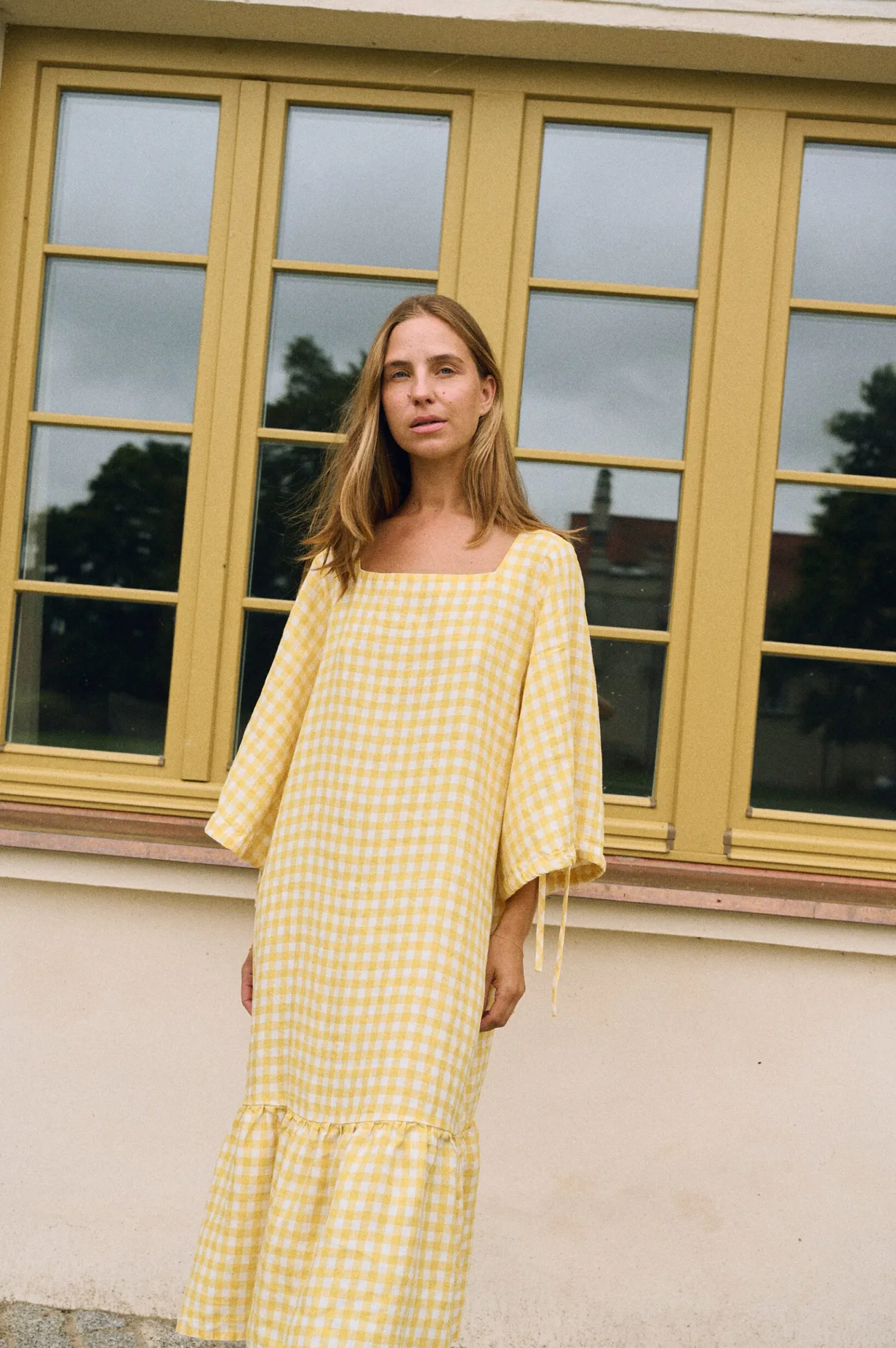 Minimalist yellow gingham linen midi dress with square neckline, loose sleeves, and gathered hem