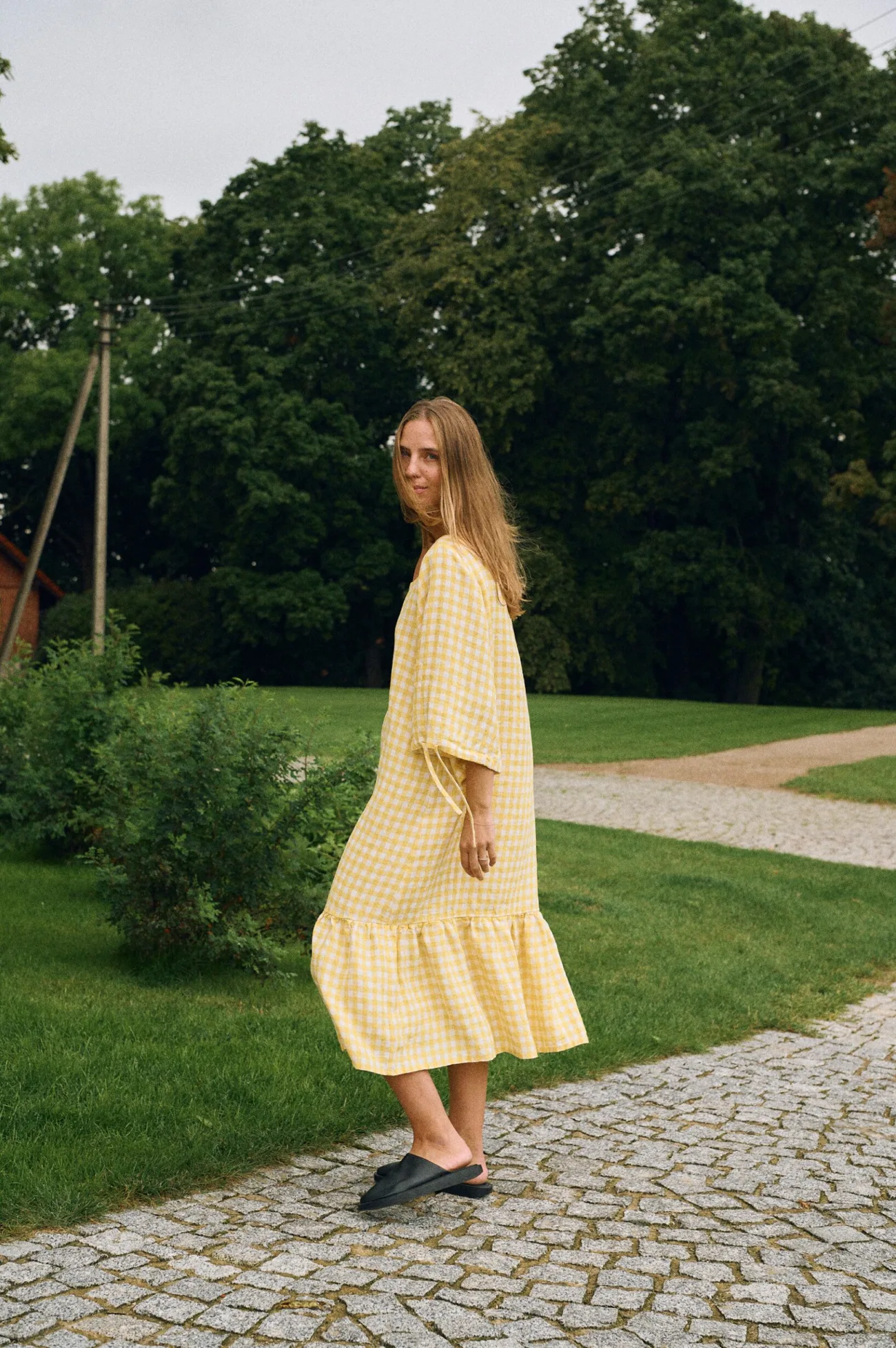 Side view of yellow gingham linen midi dress with relaxed fit, elbow-length sleeves, and gathered hem