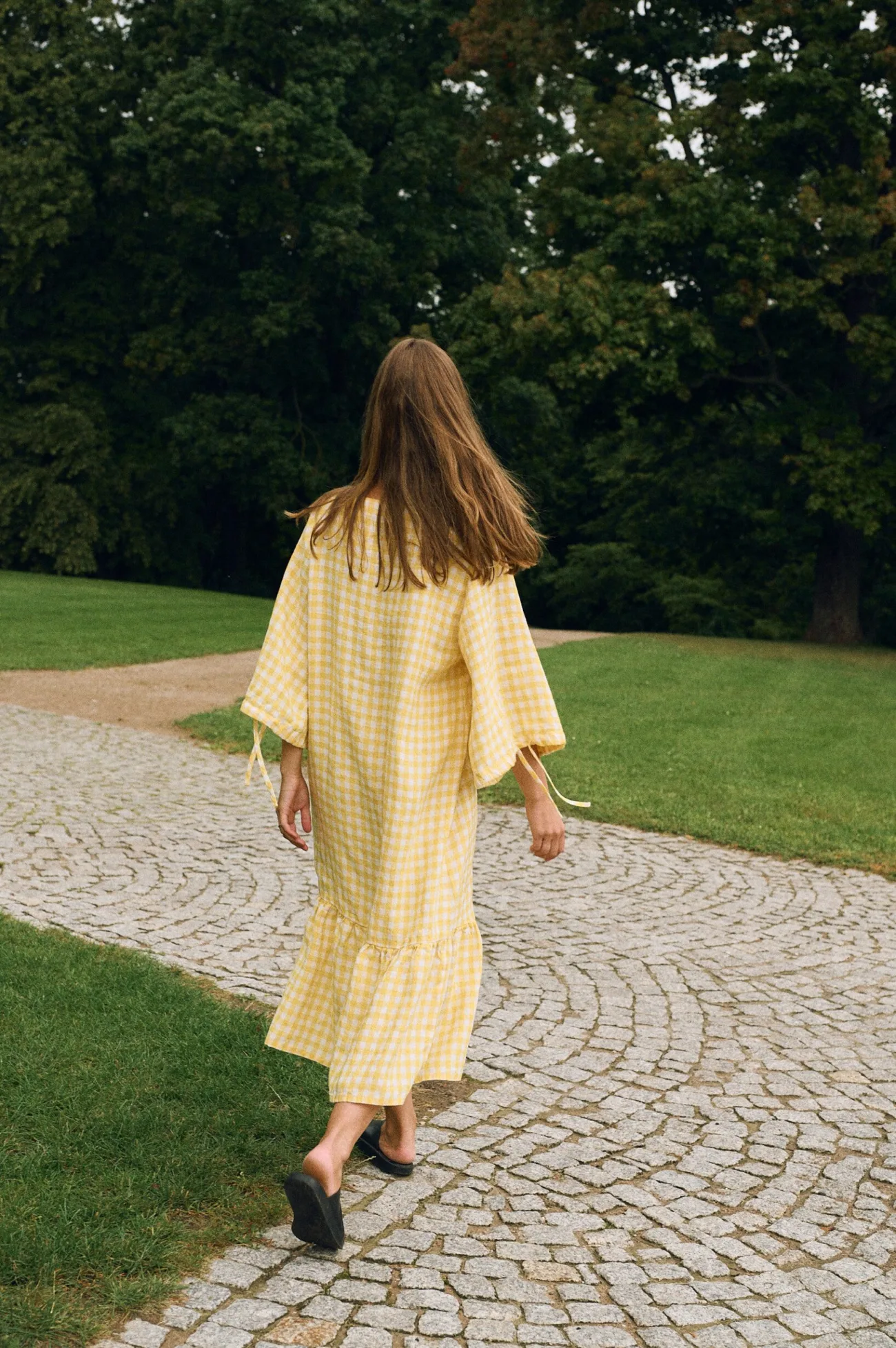 Back view of yellow gingham linen midi dress with relaxed fit, elbow-length sleeves, and gathered hem