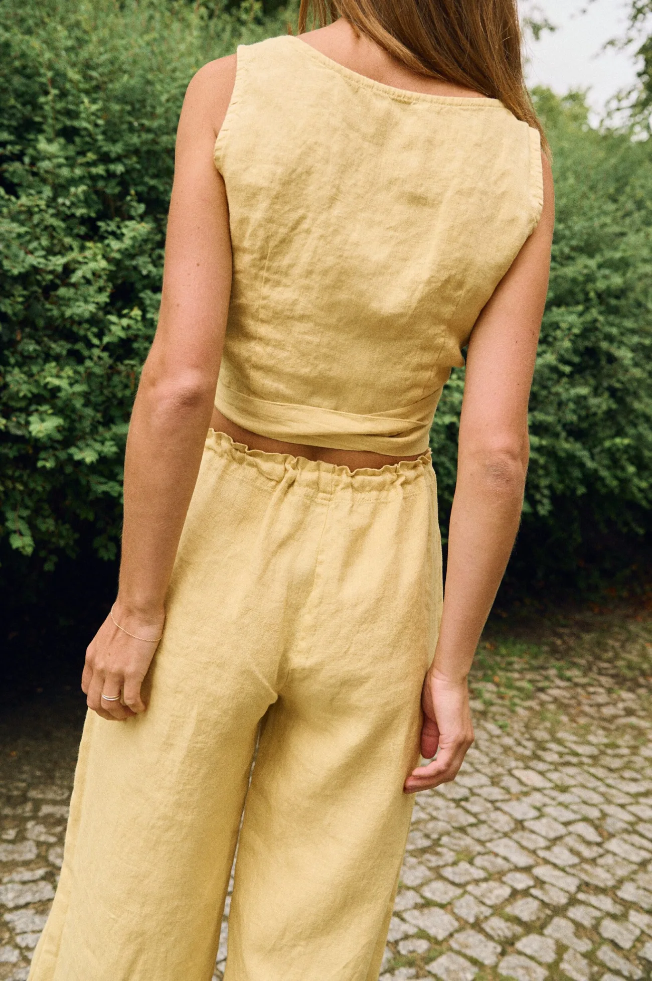 Butter yellow linen wrap top and wide-leg linen trousers with elastic waist, shown from the back in a relaxed summer outfit
