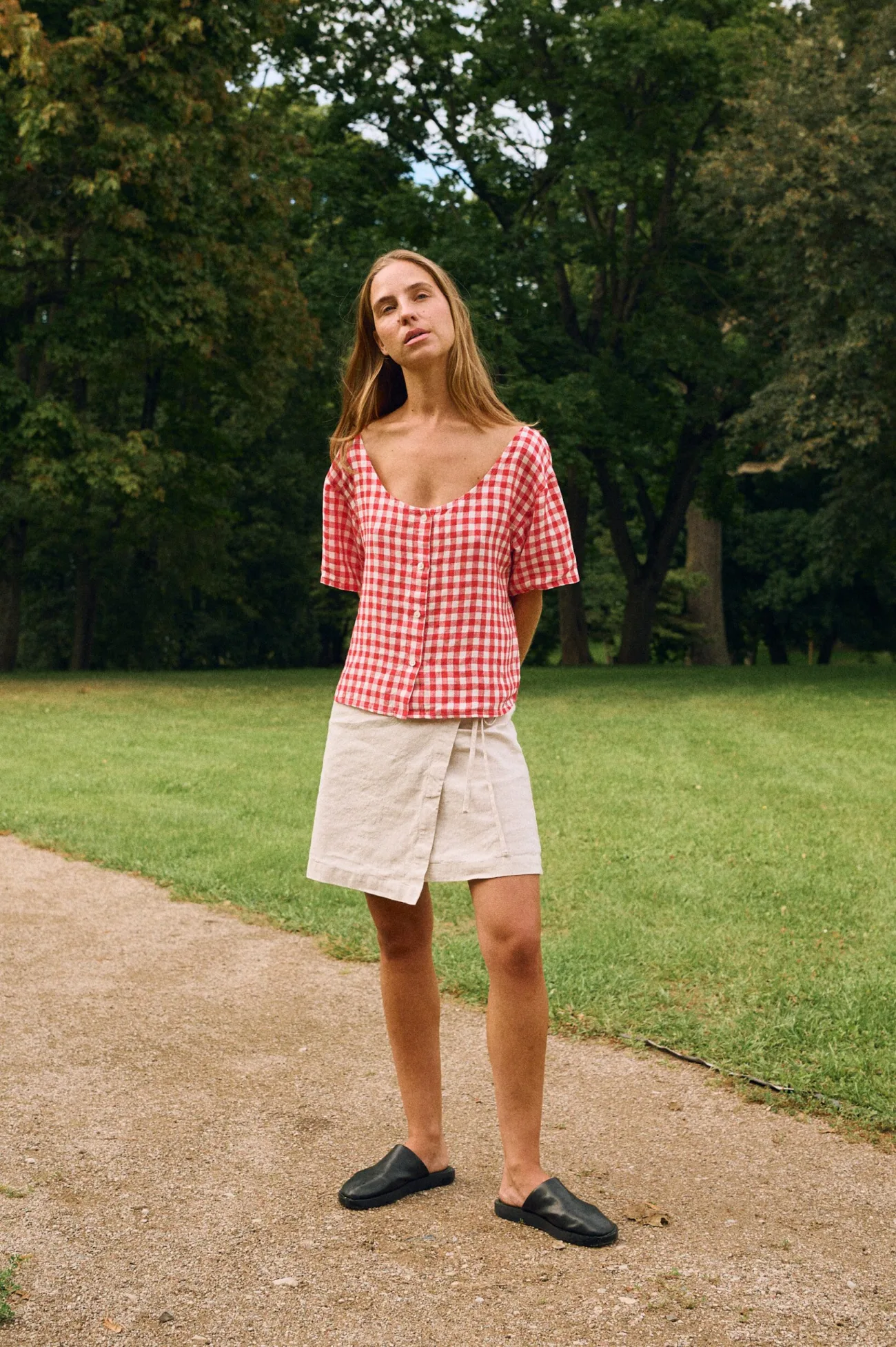 White cotton-linen blend wrap skirt featuring adjustable side ties and soft drape, paired with red gingham blouse