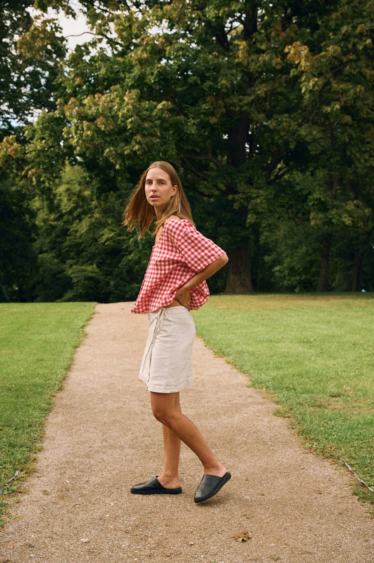 Woman wearing a red gingham linen short-sleeve top with relaxed fit paired with a natural linen cotton blend wrap skirt