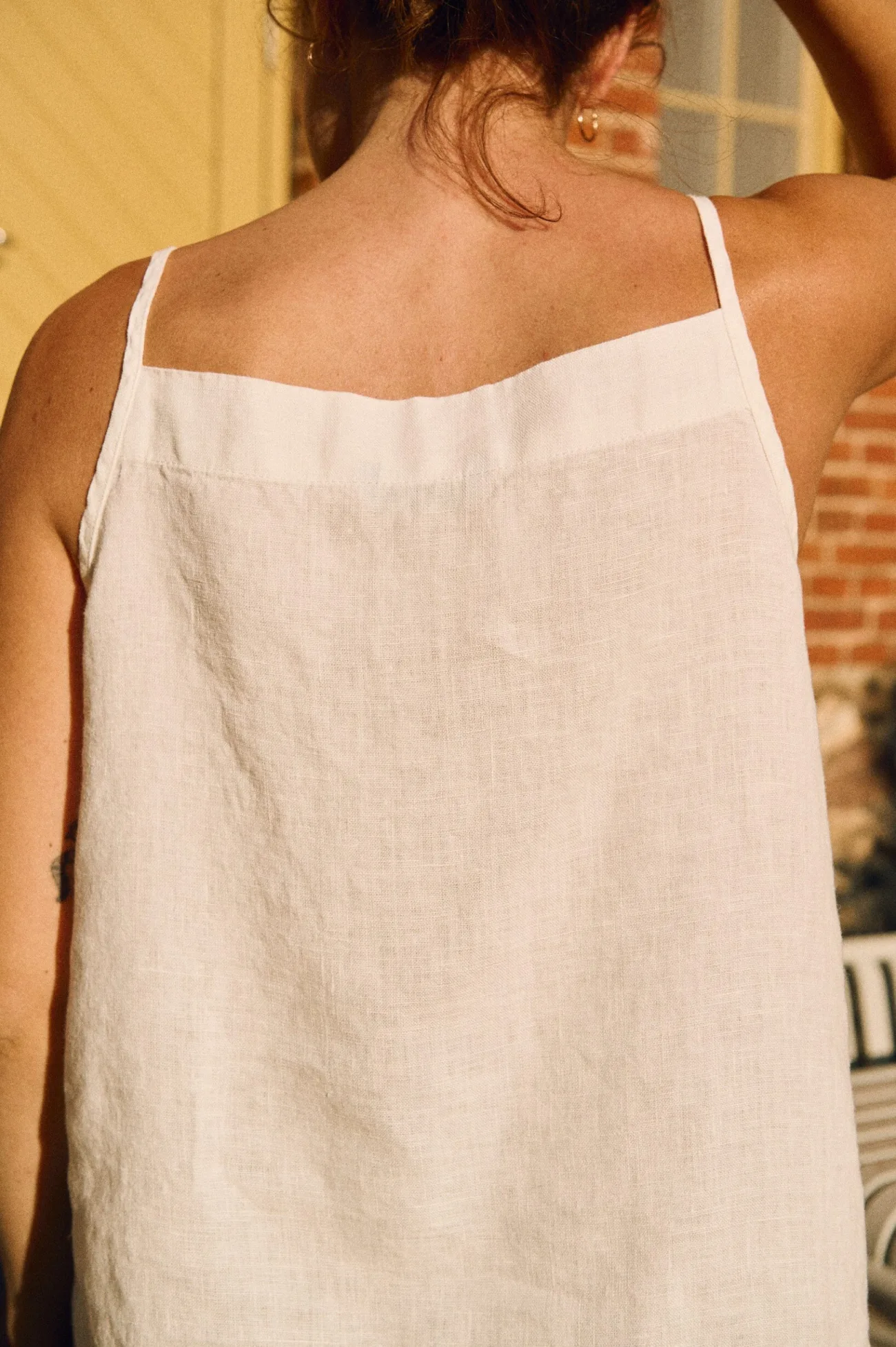 Back view of milky white linen camisole top with straight neckline and thin straps