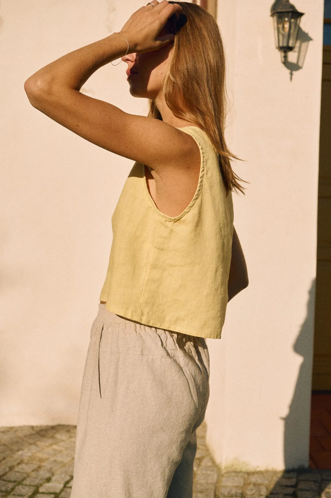 Butter yellow sleeveless linen tank worn with relaxed cotton-linen trousers