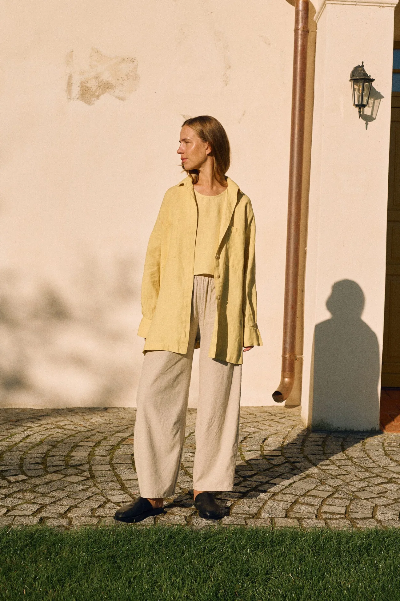 Butter yellow oversized linen shirt layered over matching tank and natural cotton-linen blend trousers