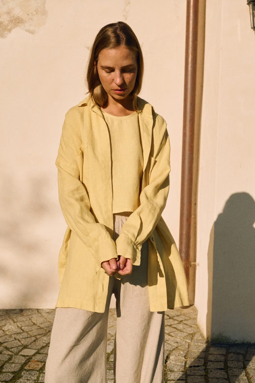 Butter yellow oversized linen shirt with dropped shoulders layered over matching tank and natural trousers