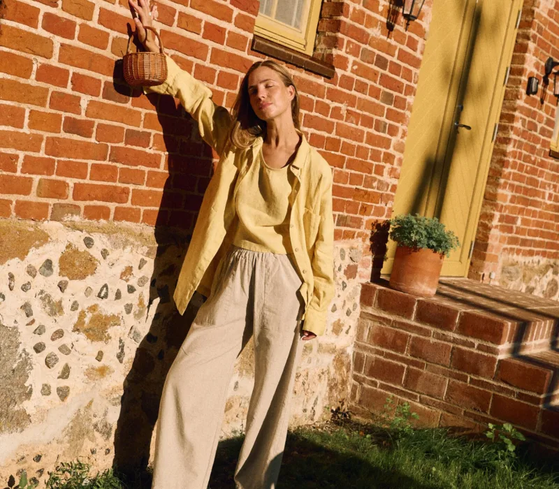 High-waisted natural cotton-linen blend trousers layered with butter yellow linen tank and oversized shirt