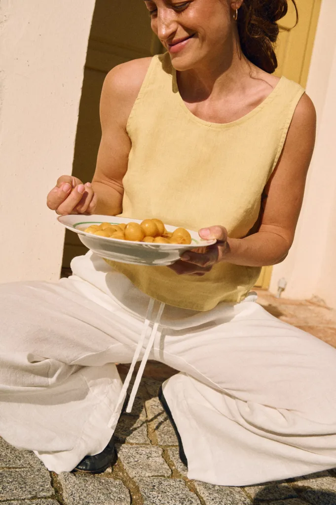 Butter yellow sleeveless linen top styled with white wide-leg linen trousers featuring a drawstring waistband