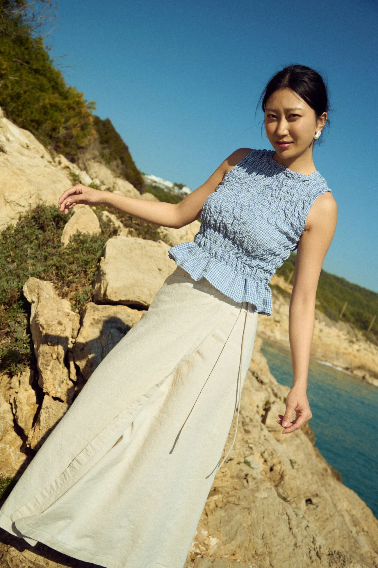 White cotton blend wrap maxi skirt with side ties, paired with a dusty blue mini gingham linen smocked sleeveless top with peplum hem