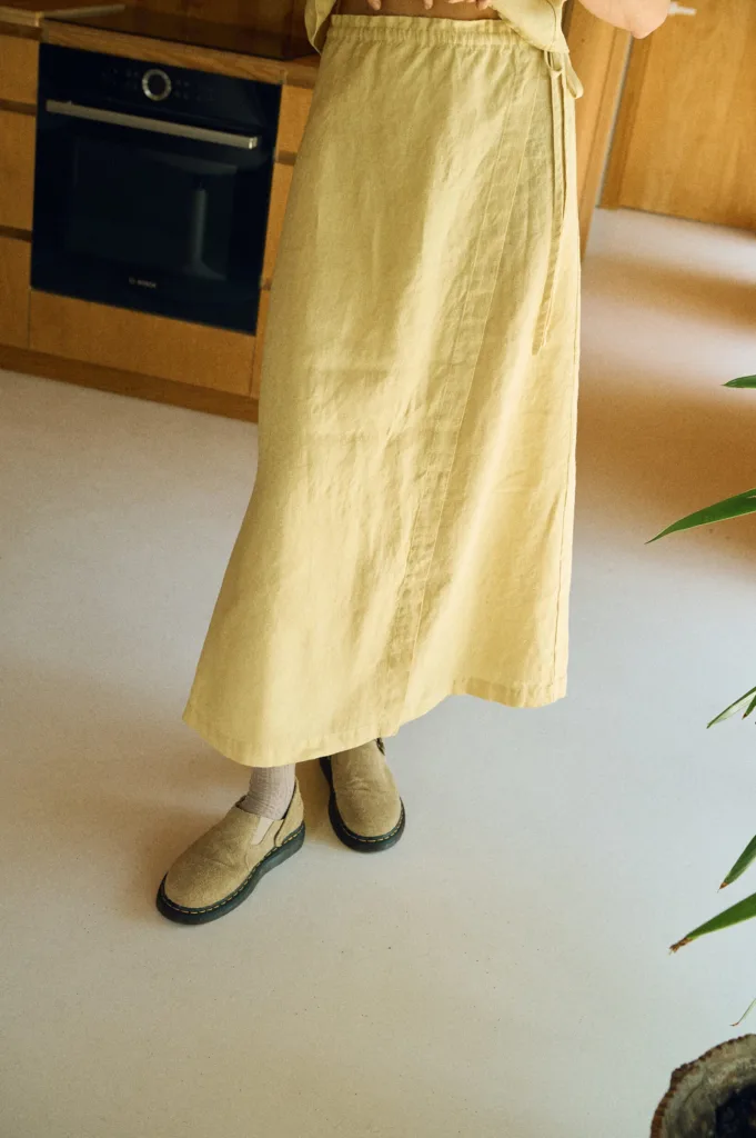 Close-up of a butter-colored linen wrap skirt featuring a flat front and long side ties