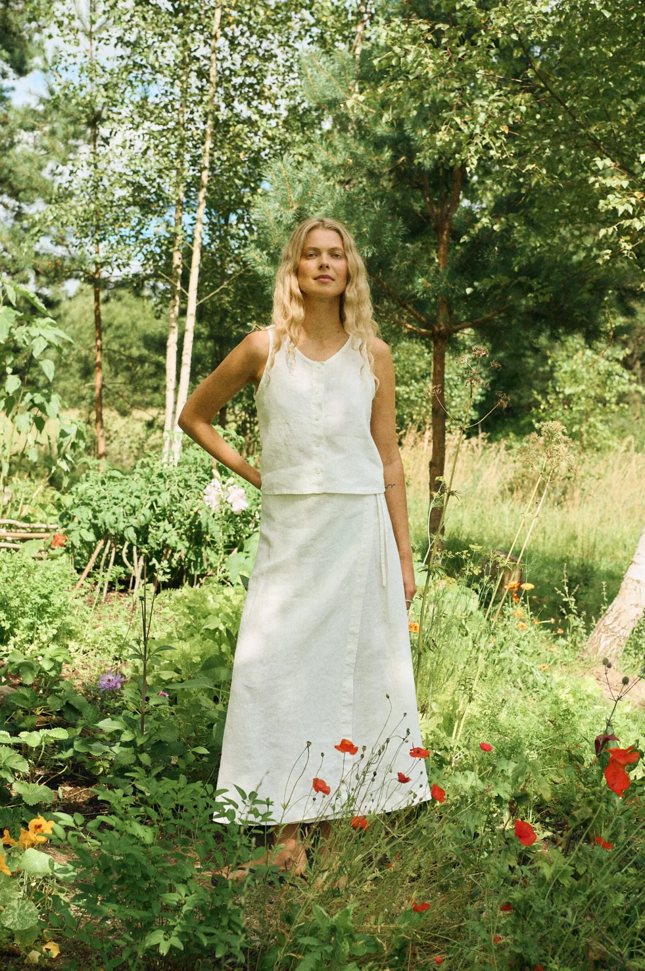 Model wearing a white linen sleeveless top paired with a matching white linen wrap skirt