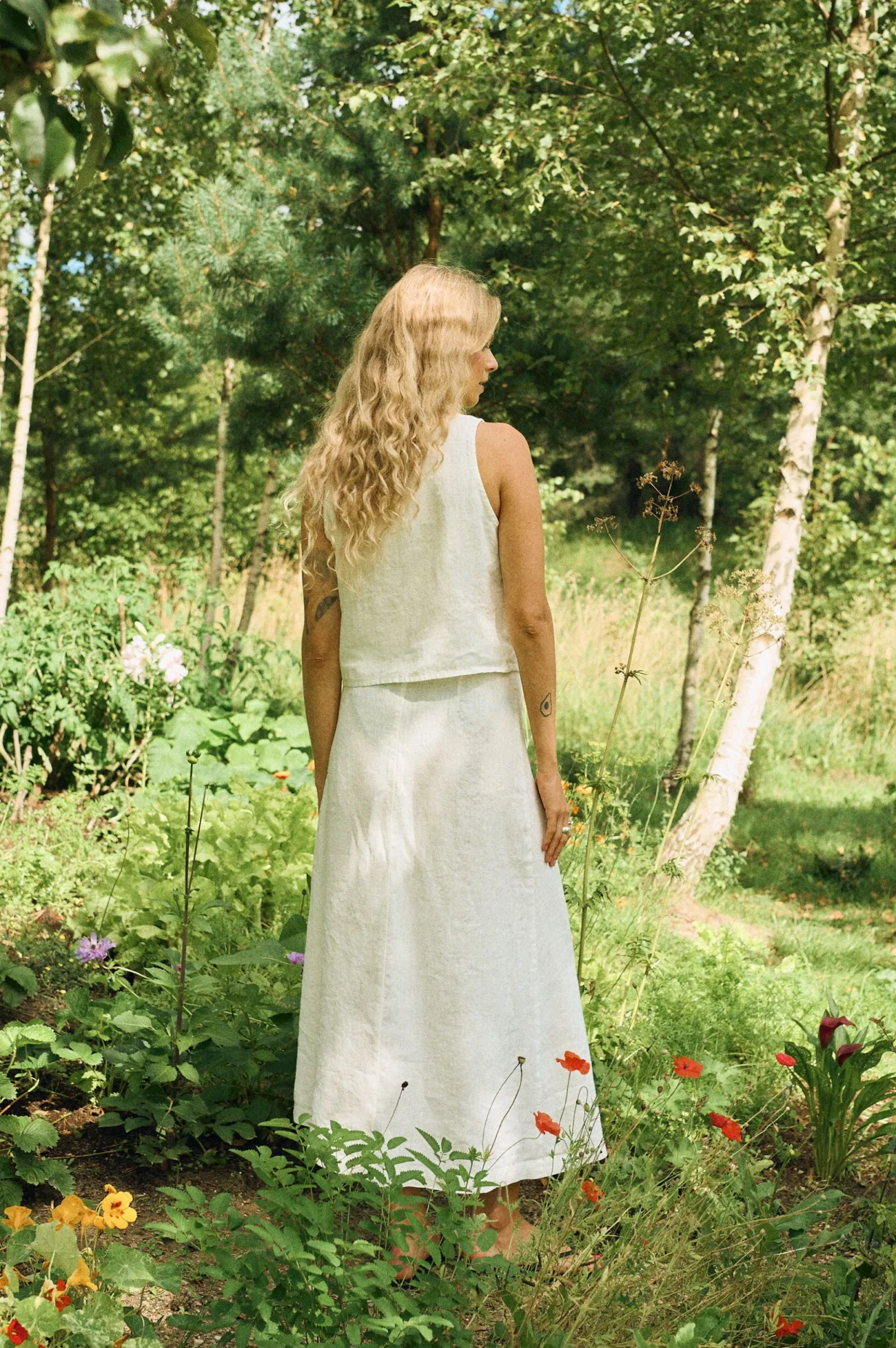 Back view of a sleeveless milky white linen top paired with a matching high-waisted wrap skirt featuring long tie closures